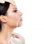 Beautiful young woman getting botox cosmetic injection in her fa